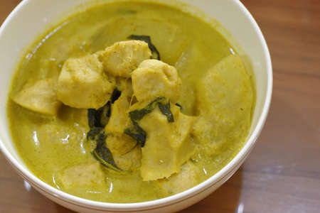 Green curry chicken soup with coconut milk in a bowl on wooden tableの写真素材