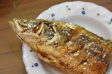 Fried fish with sesame and salt on a white plate.の写真素材