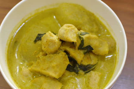 Green curry with chicken in white bowl on wooden table, Thai foodの写真素材