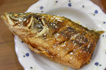 Fried mackerel with sesame seeds on a plate.