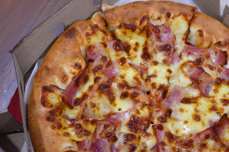 Pizza with ham and cheese in a cardboard box. Close-up.の写真素材