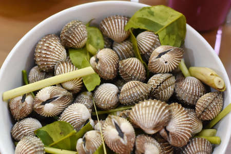 Fresh cockles in a bowl on wooden table, ready to eatの写真素材