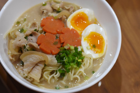 Rice noodle soup with pork and egg in white bowl.