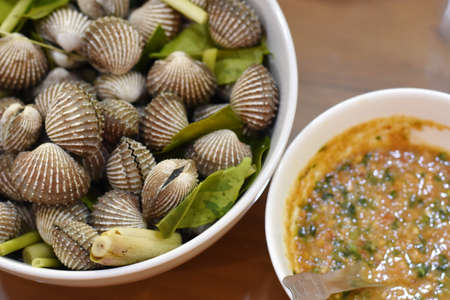 Steamed clams with spicy sauce on wooden table, stock photoの写真素材