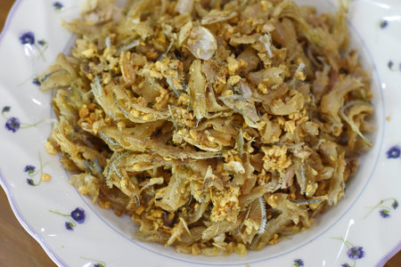 Fried anchovies with garlic in white dish on the table.の写真素材