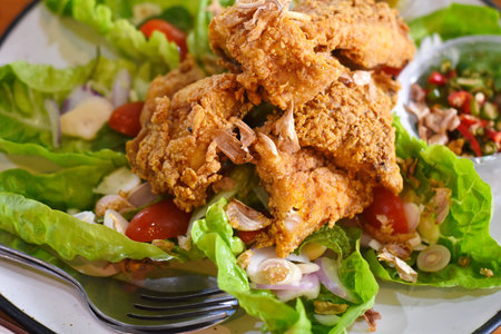 Crispy fried chicken salad with lettuce, onion, tomato and chili