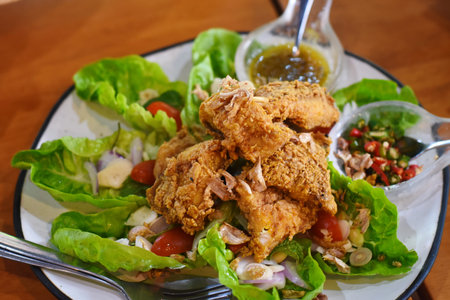 Fried chicken salad with spicy sauce on wooden table. Thai food