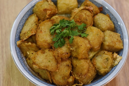 Fried potatoes in a bowl with parsley on a wooden table