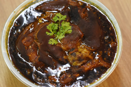 Braised pork in black soy sauce with coriander on wooden table