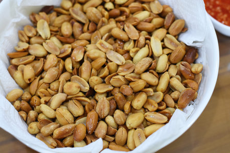 Roasted peanuts in a paper bag on a wooden table close-up