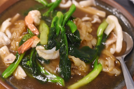 noodle soup with shrimp and kale in brown bowl close upの写真素材