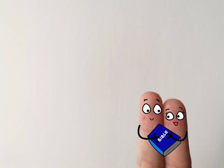 Two finges are decorated as two person. They are holding a bible.の写真素材