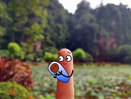 One finger is decorated as a person. She is holding a baby with different skin color.の写真素材