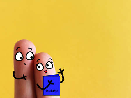 Two fingers are decorated as a couple. They are discussing about their insurance package.の写真素材
