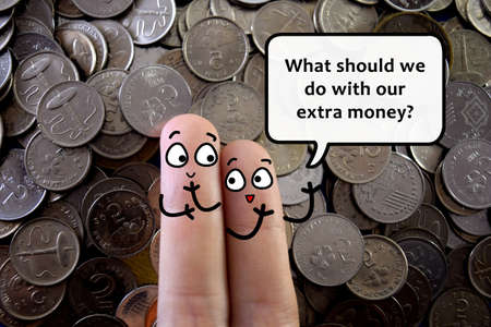Two fingers are decorated as two person. One of them is asking about how should they manage their extra money.の写真素材