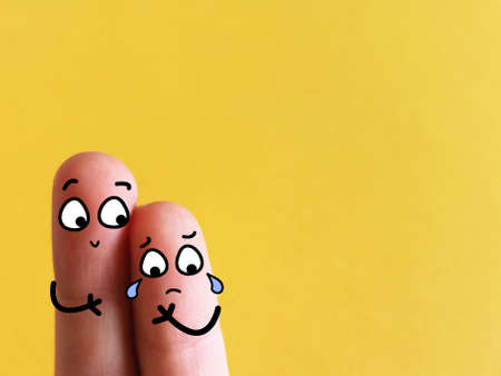 Two fingers are decorated as two person. One of them is crying . Another one is comforting him.の写真素材