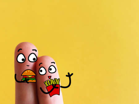 Two fingers are decorated as two person. They are eating fast food.の写真素材