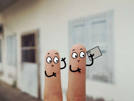 Two fingers are decorated as two person. They are at the back yard.They are taking video happily.の写真素材