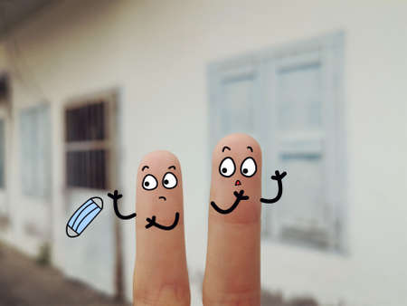 Two fingers are decorated as two person. They are at the back yard. One of them is throwing used mask on floor.の写真素材
