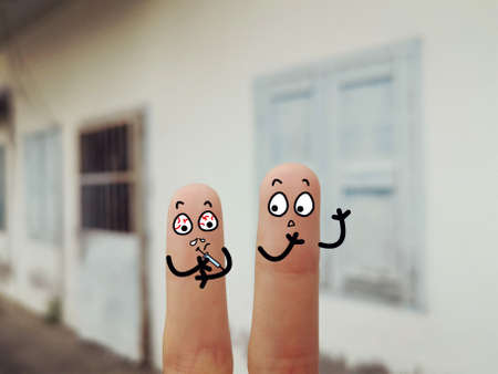 Two fingers are decorated as two person. They are at the back yard. One of them is injecting medicine to body.の写真素材