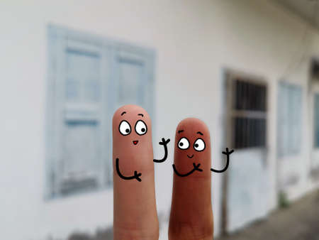 Two fingers are decorated as two person. They have different skin color.の写真素材