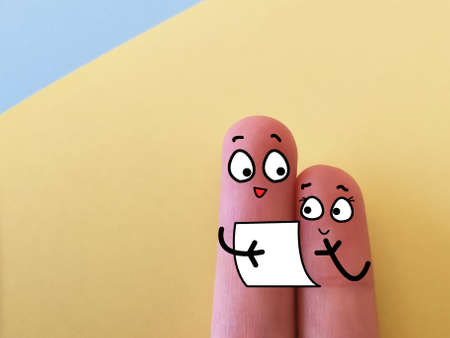 Two fingers are decorated as two person. They are reading a letter.の写真素材
