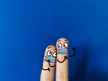 Two fingers are decorated as two person wearing mask during pandemic. One of them is asking question about coronavirusの写真素材