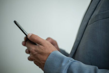 Businessman in casual suit sending text messages with his smartphone