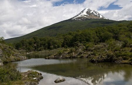 A well forested mountain with a snow covered peak - Tierra Del Fuegoの写真素材