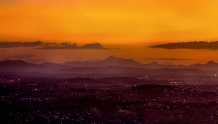 View of a foggy mountain sunset, with urban residences in foregroundの写真素材