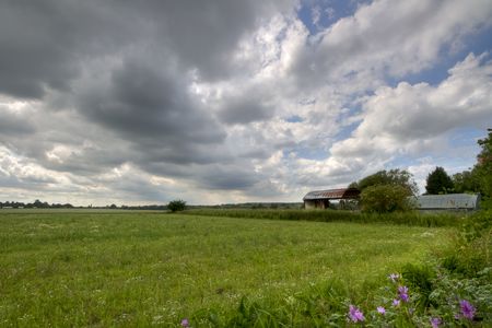 View of a green field and farm buildings, set against a moody sky. Image captured in Kent, England.の写真素材