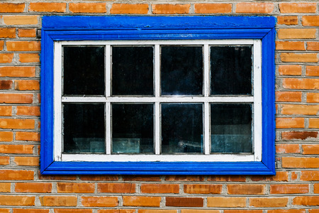 Old barn with a vintage wooden window of blue color and a brick wallの写真素材