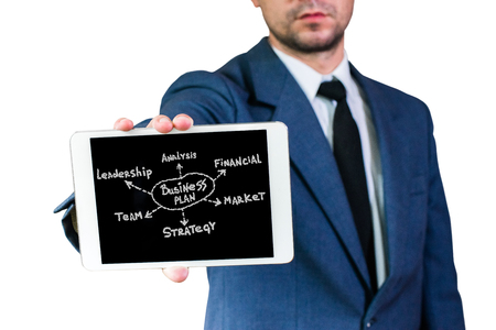 Young businessman in a jacket and white shirt, holding a tablet with business planの写真素材
