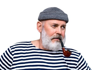 Portrait of a sailor in marine uniform. A middle aged man with a gray beard holding a pipe.の写真素材