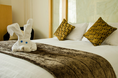 White brown bedroom with white plush toy on the brown bed cover.の写真素材