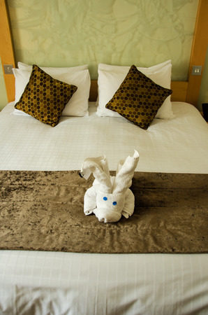 White brown bedroom with white plush toy on the brown bed cover.の写真素材