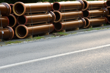 Stacks of pipes next to asphalt road.の写真素材