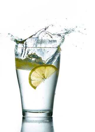 Three lemons are falling into the glass of water.の写真素材