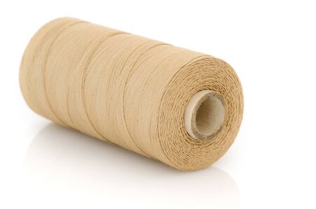 Reel of beige thread isolated on white background.の写真素材