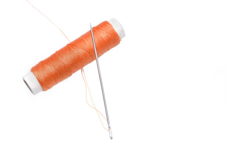 Reel of orange thread and needle isolated on white background.の写真素材