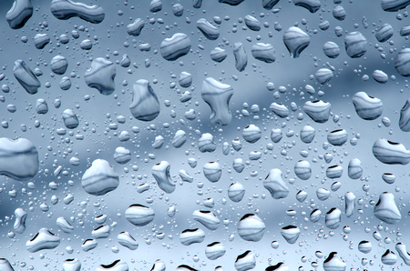 Water drops against blue gray background, wet glass surface.の写真素材