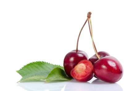 Three and one cutted cherries next to leaves.の写真素材