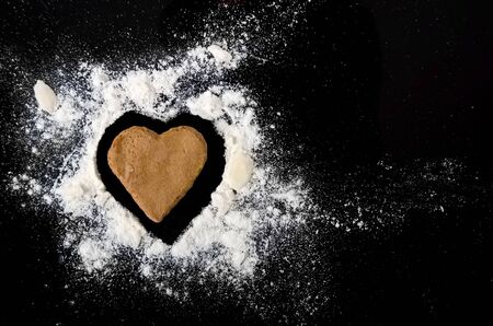 Gingerbread heart with almond and flour isolated on black background.の写真素材