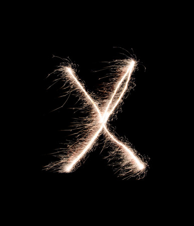 Letter X drew with spakrs on a black background.の写真素材