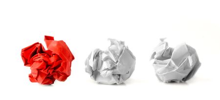 Red paper ball next to two white ones as a symbol of difference and variety of society and ideas.の写真素材