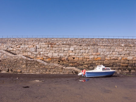 Boat on sand, steps lead down from Trefor harbour wall. Wales UK.の写真素材