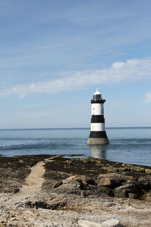 Path leading to a lighthouse in the sea.の写真素材