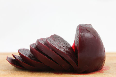 Cooked beetroot sliced on chopping board against a white background.の写真素材
