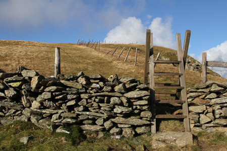 Wooden steps over a stone wall giving public access to national park land.の写真素材