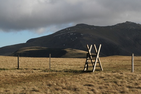 Wooden style over a fence on green grass on a mountain.の写真素材